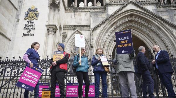 Nurses stand outside the High Court in central London, wher<em></em>e the government is bringing a challenge over the planned strike action by the Royal College of Nurses (RCN) in the long-running dispute over pay, in London, Thursday April 27, 2023. (James Manning/PA via AP)