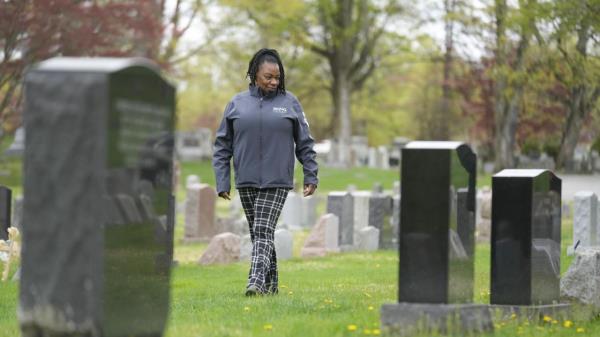 Debra Long walks near the tombstone of her son, Randy Long, in Poughkeepsie, N.Y., April 19, 2023. An AP examination of data from 23 states shows that Black people are disproportio<em></em>nately denied aid from programs that reimburse victims of violent crime. (AP Photo/Seth Wenig)