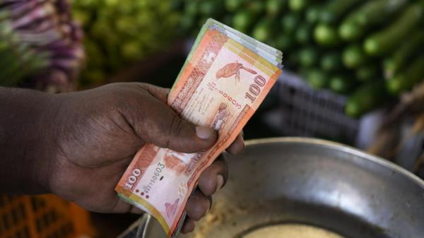 A vendor holds currency notes as he sells vegetables at a market place in Colombo, Sri Lanka, Thursday, June. 1, 2023. The Central Bank of Sri Lanka reduced its interest rates Thursday, June 1, 2023, for the first time since the island nation declared bankruptcy last year. Stern fiscal controls, improved foreign currency income and help from an Internatio<em></em>nal Mo<em></em>netary Fund program has resulted in inflation slowing faster than expected. (AP Photo/Eranga Jayawardena)