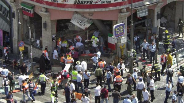 EDS NOTE: GRAPHIC Co<em></em>nTENT - FILE - Police and medics surround the scene of a bomb explosion in a restaurant downtown Jerusalem, Aug. 9, 2001. An Israeli hospital says a woman critically wounded in a 2001 suicide bombing at a Jerusalem restaurant has died. Her death marked the sixteenth fatality from that attack. (AP Photo/Peter Dejong, File)