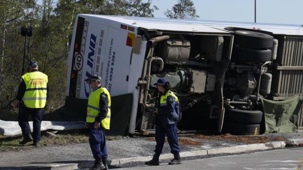 Police inspect a bus in its side near the town of Greta following a crash in the Hunter Valley, north of Sydney, Australia, Monday, June 12, 2023. The bus carrying wedding guests rolled over on a foggy night in Australia's wine country, killing and injuring multiple people, police said. (AP Photo/Mark Baker)