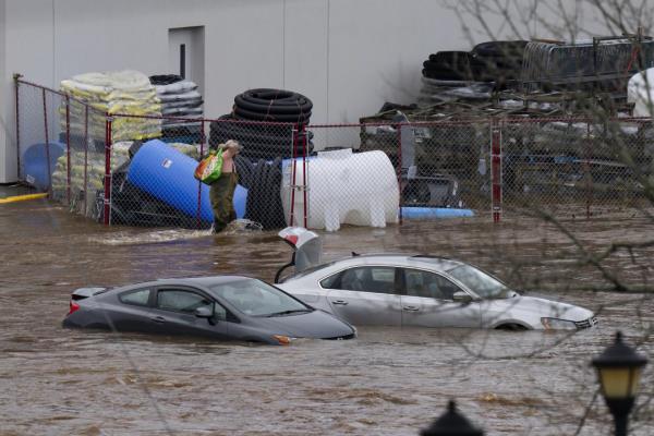 A man wearing chest waders walks past cars abando<em></em>ned in floodwaters in a mall parking lot following a major rain event in Halifax, Nova Scotia, Canada, on Saturday, July 22, 2023. (Darren Calabrese/The Canadian Press via AP)